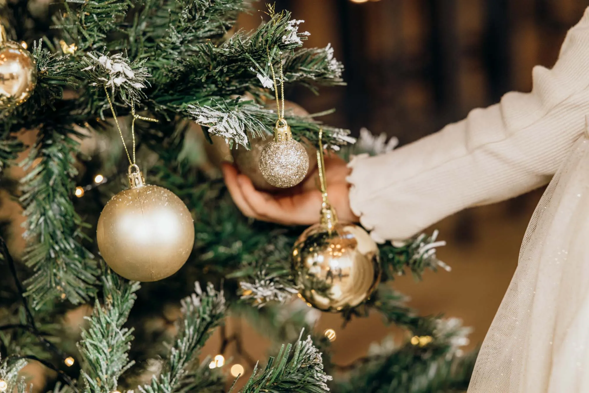 Hand schmückt einen Weihnachtsbaum mit Kugeln
